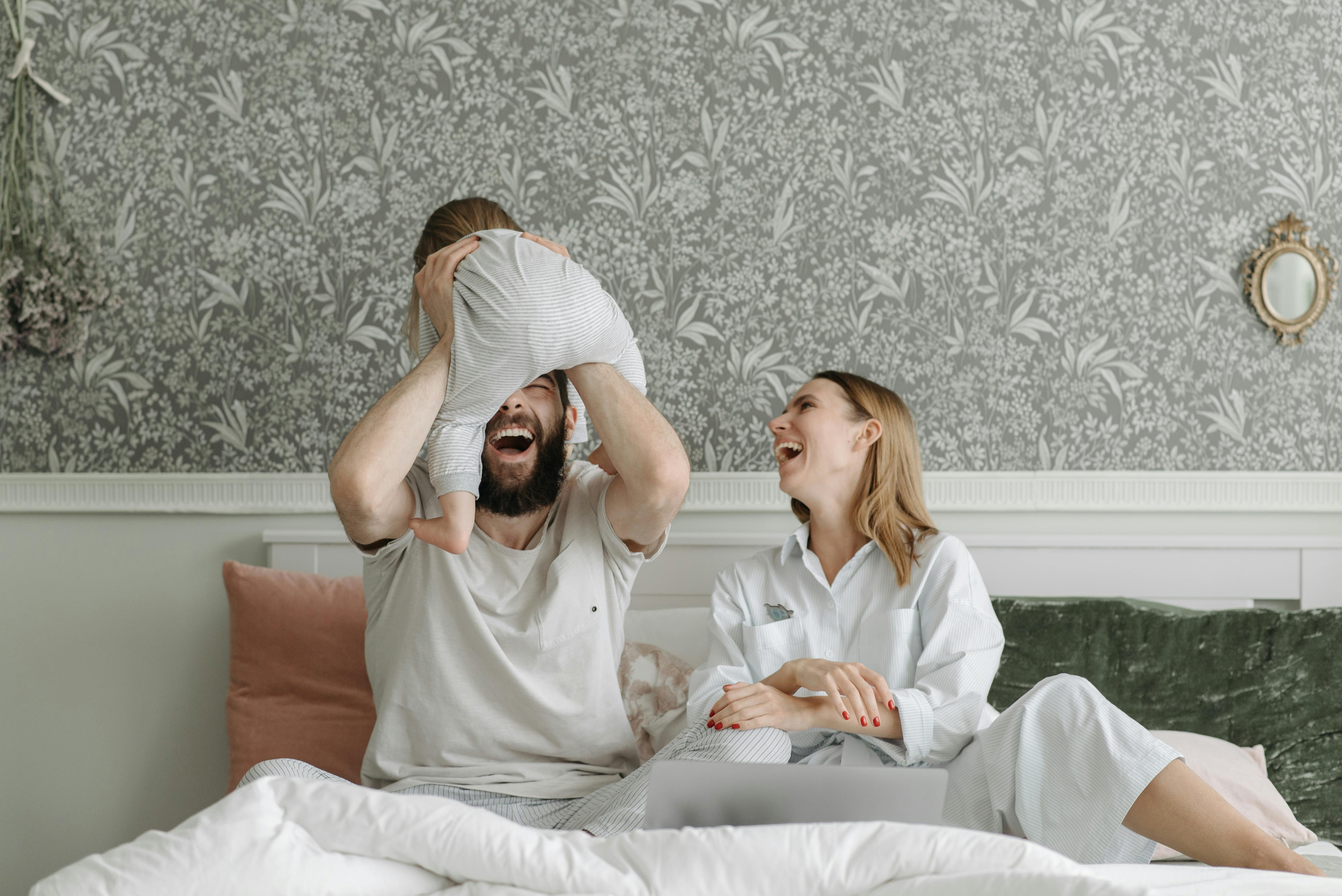 parents holding up their child in bed